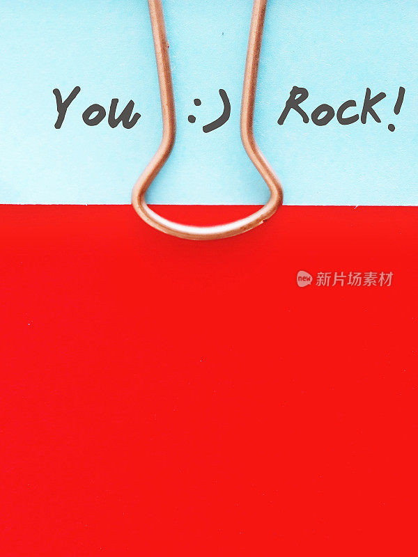 蓝色的卡片，上面写着“YOU ROCK”的文字，用红纸夹住，留出空间——对某人/团队/同事的良好表现给予赞扬或赞美
